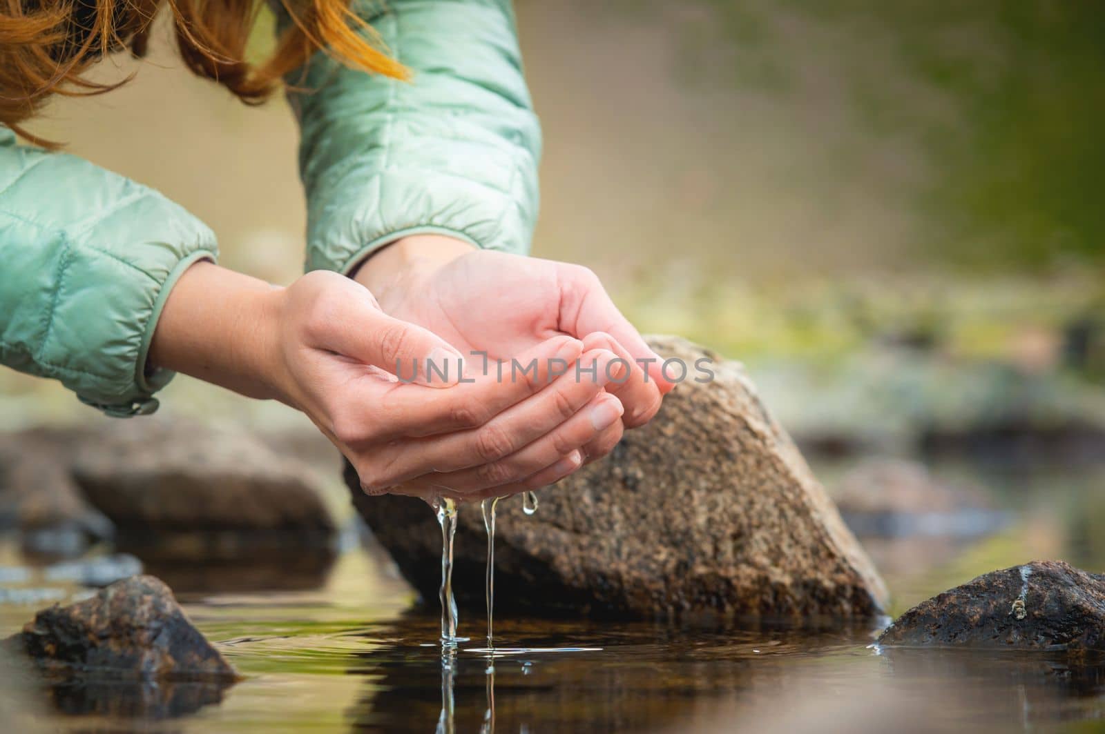 Hands and water. Close-up of a woman taking water from a mountain lake in her hands.