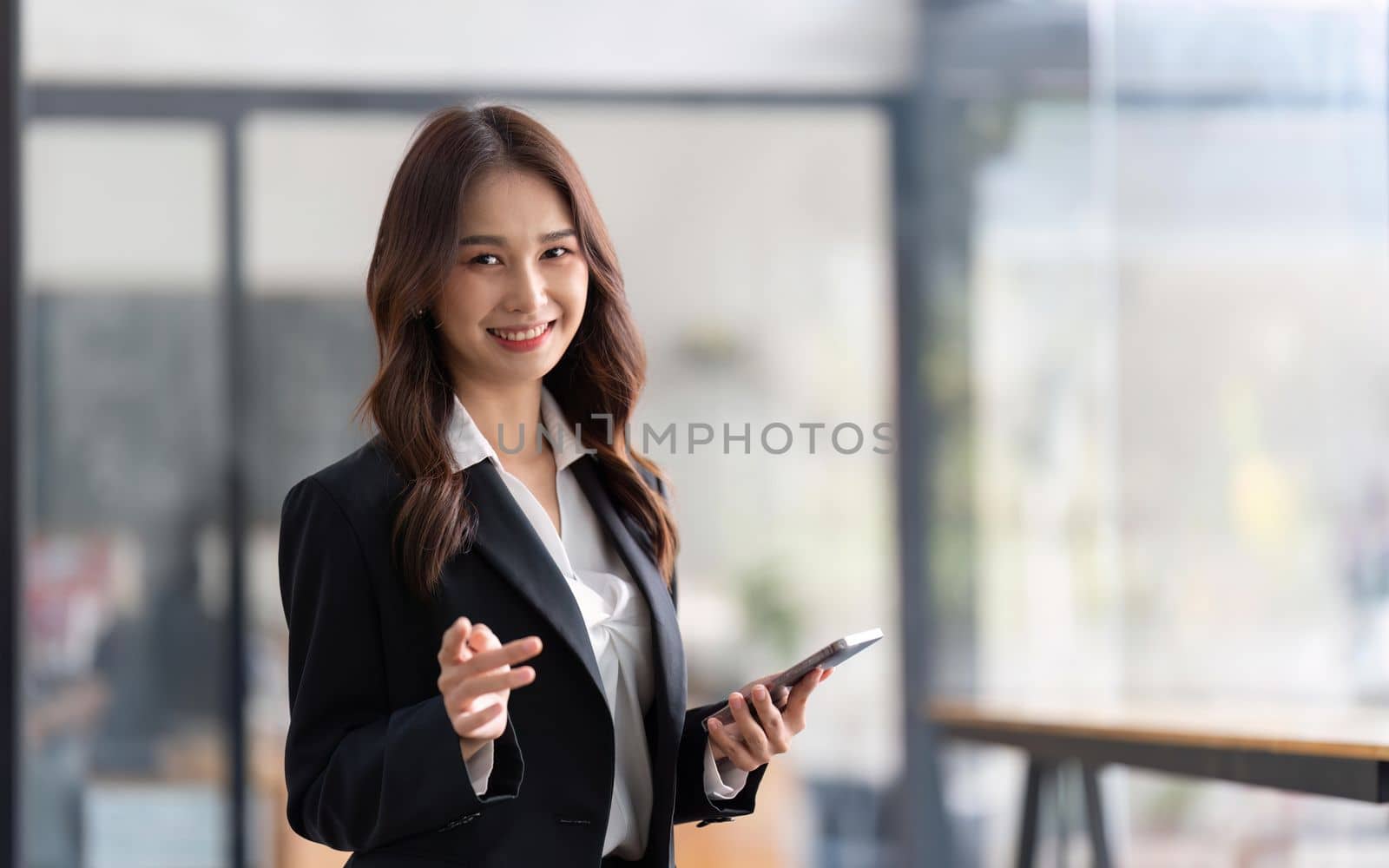 Happy businesswoman holding telephone working standing in office using mobile cell phone working.