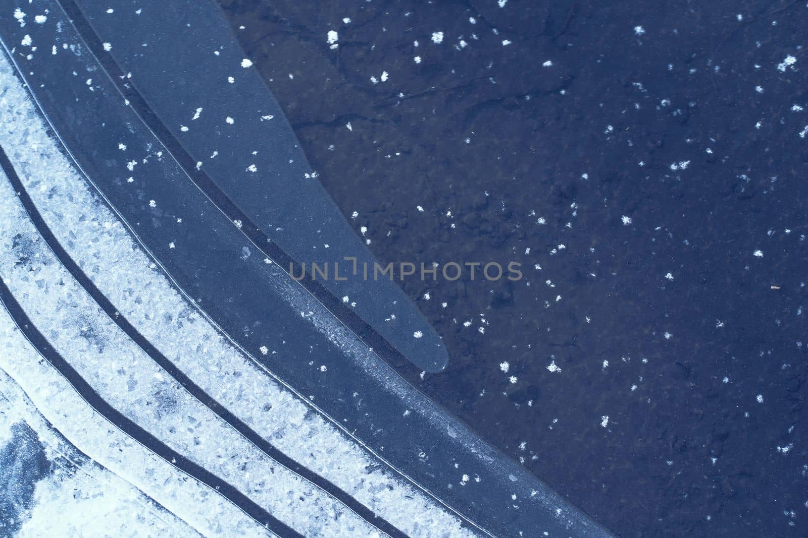 Abstract black and white toned image features a top-down view of a frozen ice background with white stripes resembling snowflakes. The intricate and delicate details of the ice create a mesmerizing pattern, making it a great background for various design projects. High quality photo