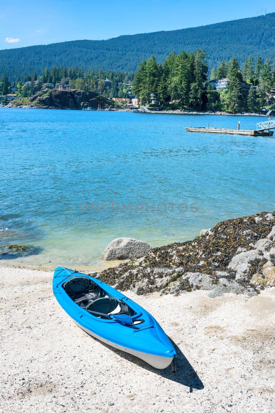 Blue lightweight canoe on a shore of Pacific ocean bay on sunny day.