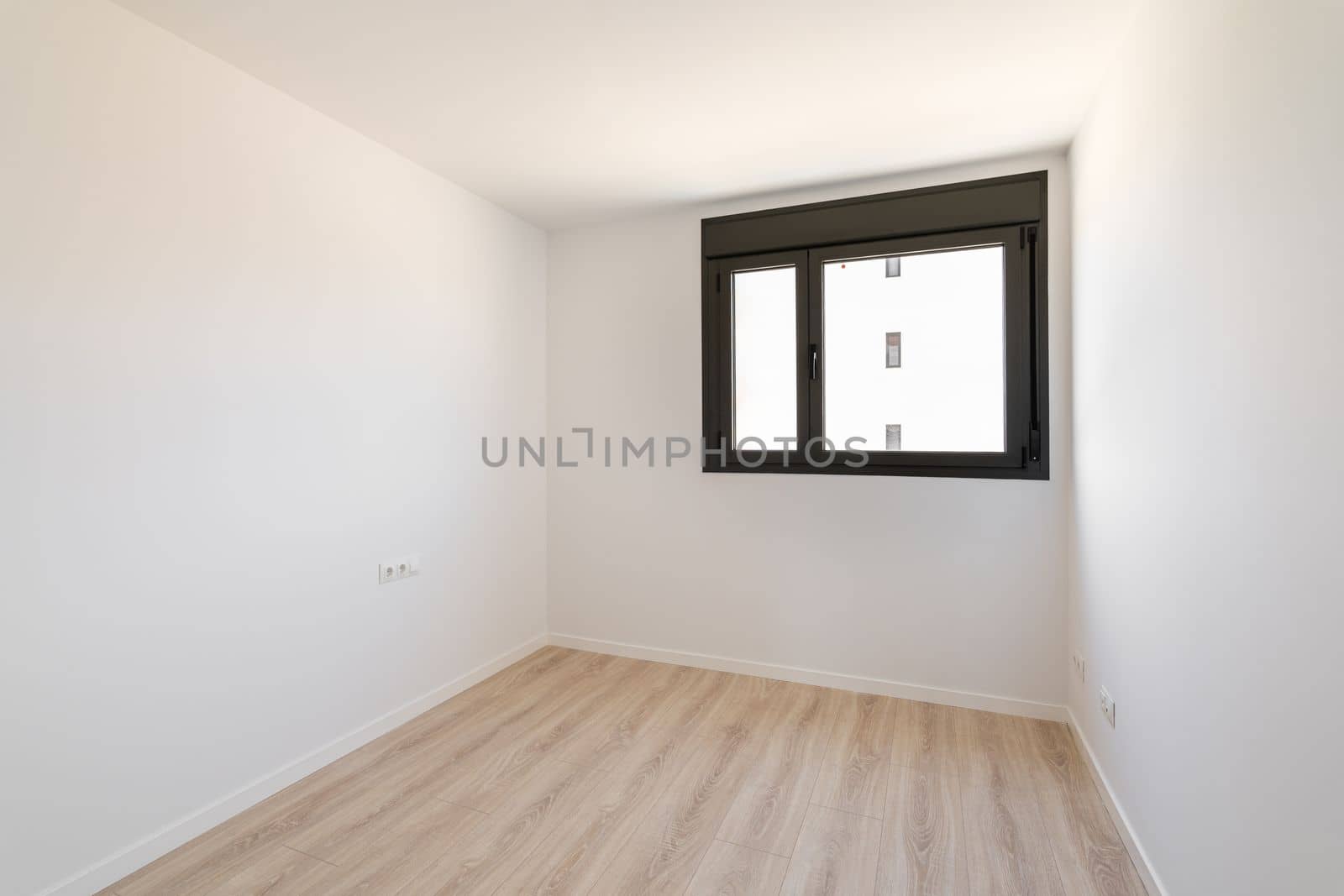 Small empty room without furniture. The floor is new light wood laminate. A window made of black plastic for airing the room. Daylight enters through the frosted glass in the window. by apavlin