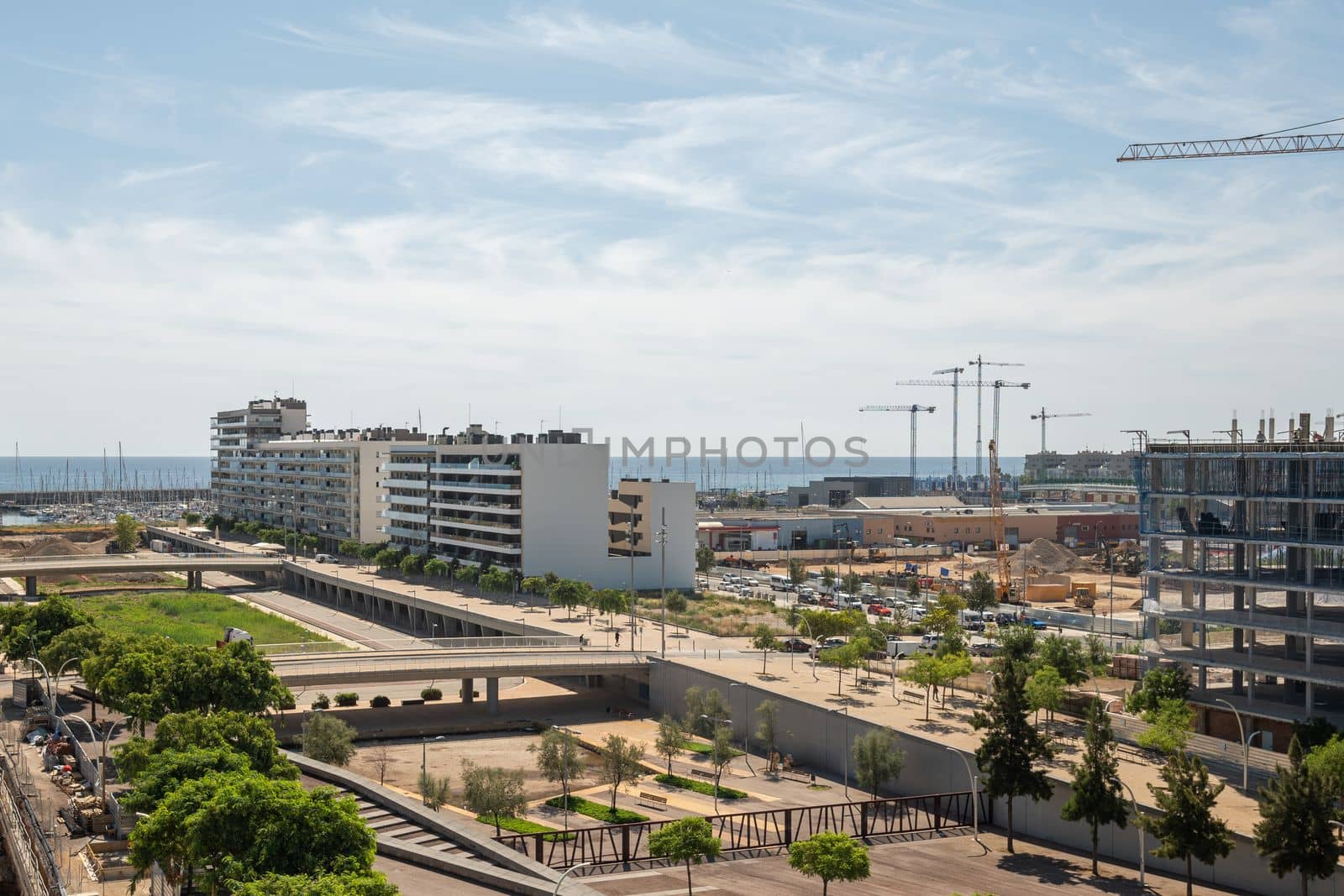 Gorg area in Barcelona, Spain, with many new and under construction residential buildings. Park areas with architectural bridges. In the distance, the ocean and blue sky merge into the horizon lines. by apavlin