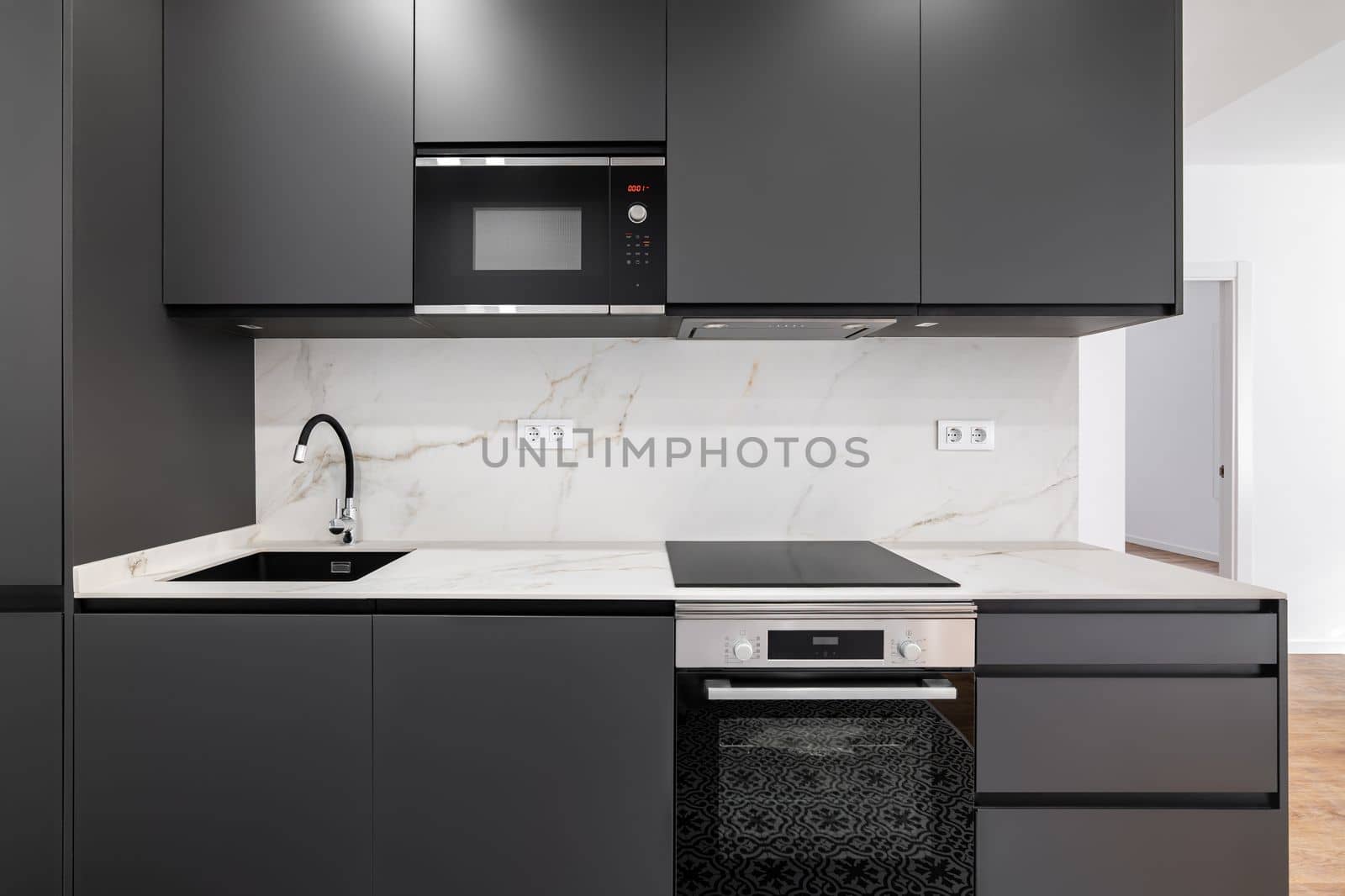 Modern minimalist kitchen with gray charcoal panels and white marble strip. The concept of a comfortable stylish cozy kitchen with expensive equipment.