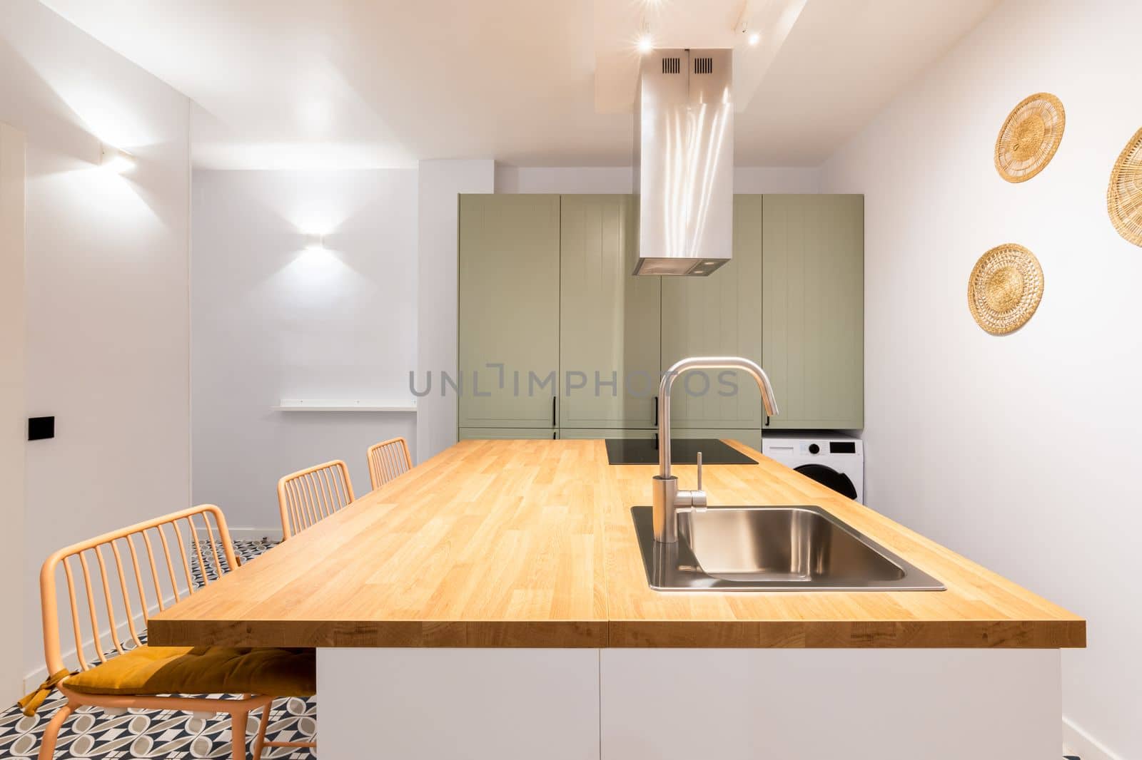 Designer kitchen with bright lighting from wall lamps. Table with sink and faucet in chromed metal. Above the electric stove, system for purifying the air from odors during cooking. by apavlin