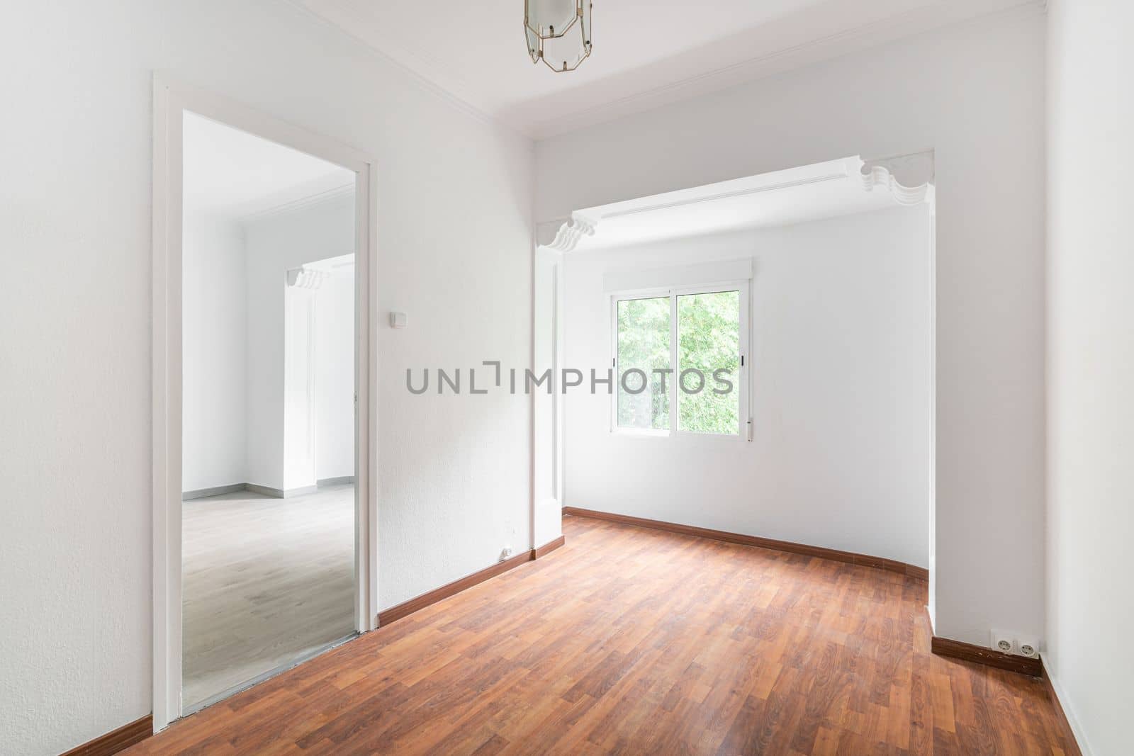 Bright, spacious empty white apartment with curly arch windows and luxury chandelier with wooden floors in dark and light shades. Concept of moving to new modern apartment.