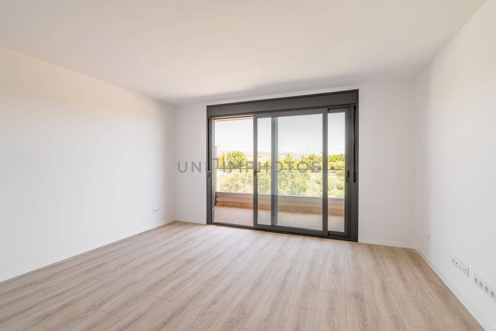 Spacious large room with wooden parquet structure and panoramic window overlooking beautiful landscape among complex of new buildings and balcony with elegant glass border. Mortgage and moving concept by apavlin