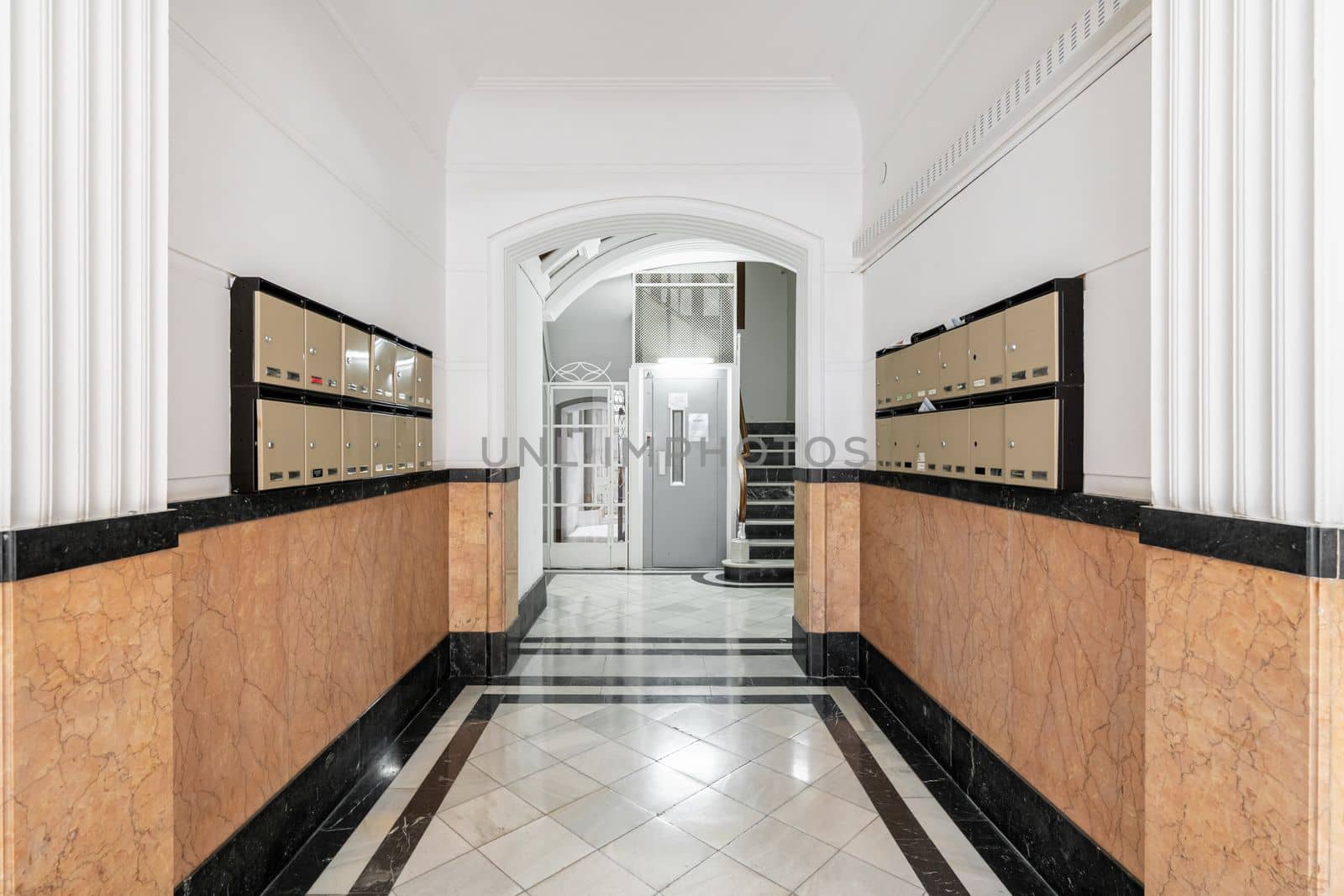 Long hall on the walls with orange marble tiles mailboxes on both sides for correspondence and letters. At the end of the hall there is a modern elevator to other floors and stairs