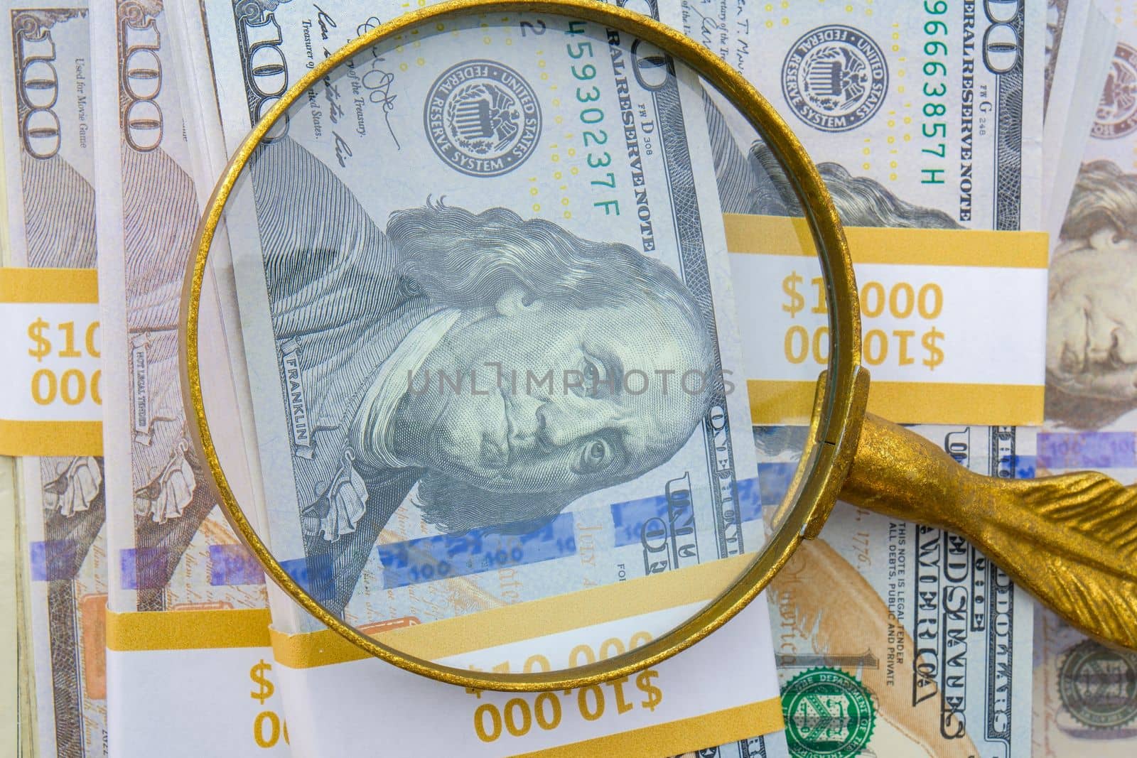 Magnifying glass showing detail of hundred dollar bills on a pile of 10,000 strap bundles. High quality photo