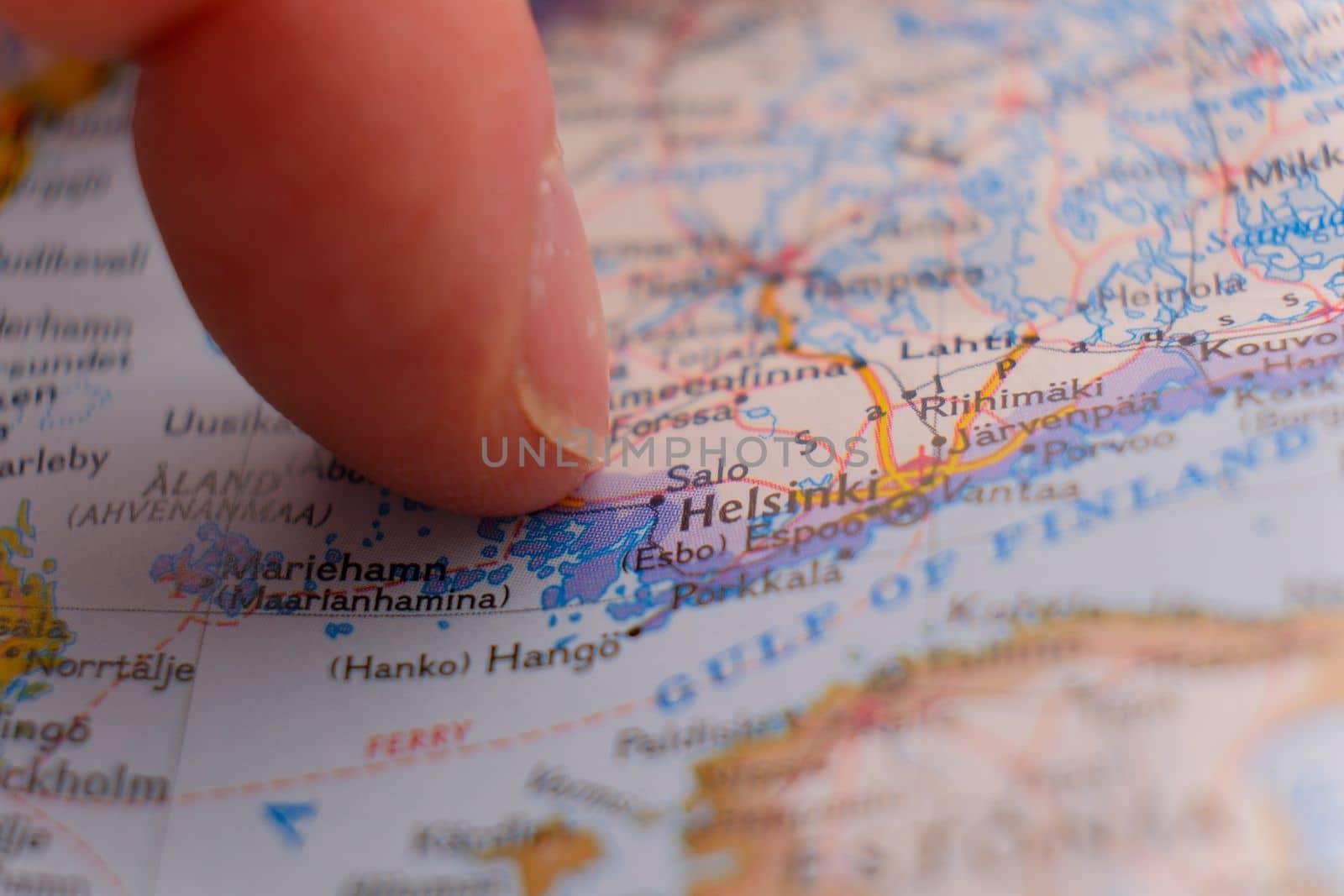 Close up of finger pointing to Helsinki, Finland on colorful map, background blur. High quality photo
