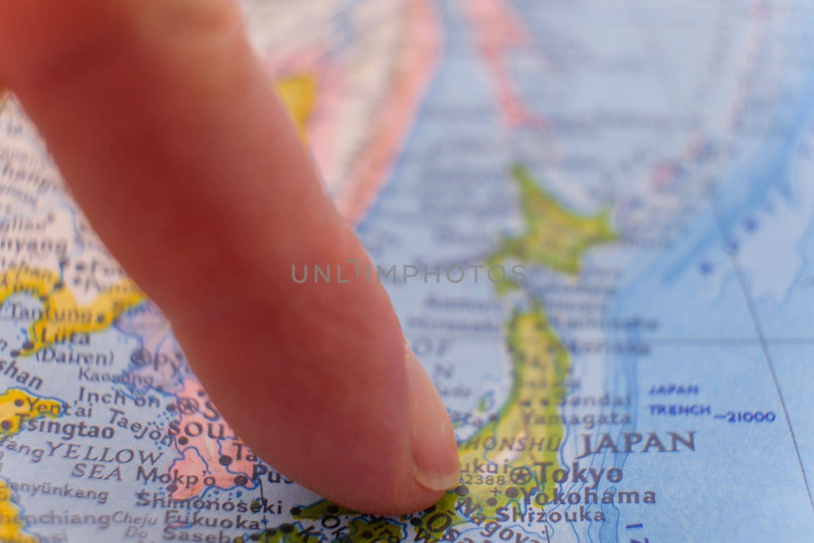 Finger pointing to Tokyo, Japan on colorful map with selective focus, shallow depth of field, background blur. High quality photo