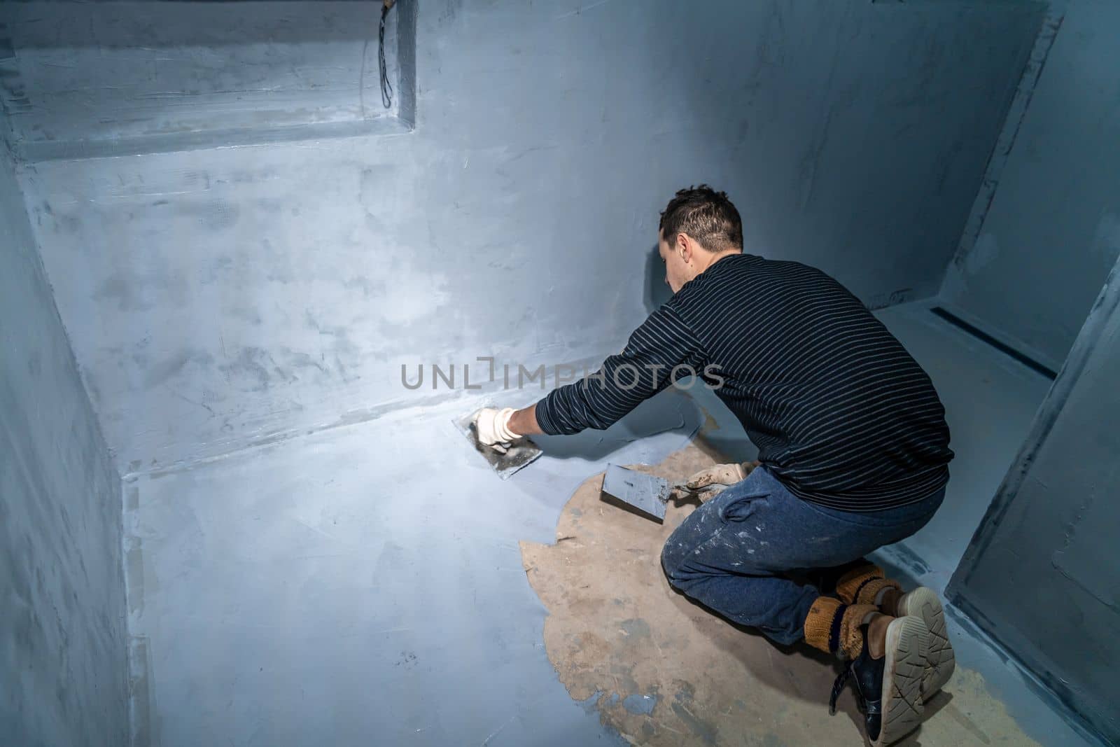 man applies insulation to a bathroom wall.