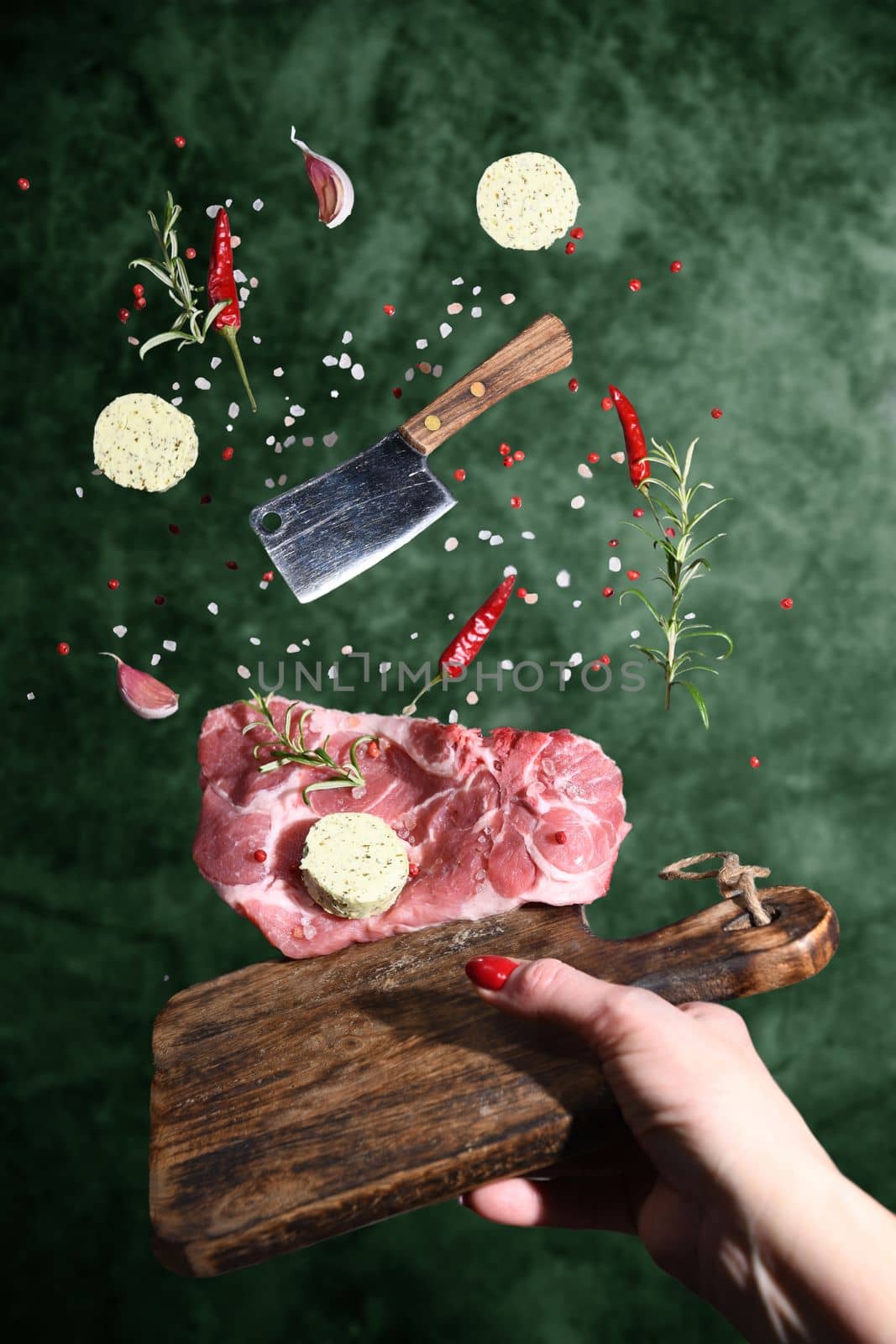 Art photo levitation of a meat steak with ingredients for frying oil spices rosemary pepper garlic on a green background. High quality photo