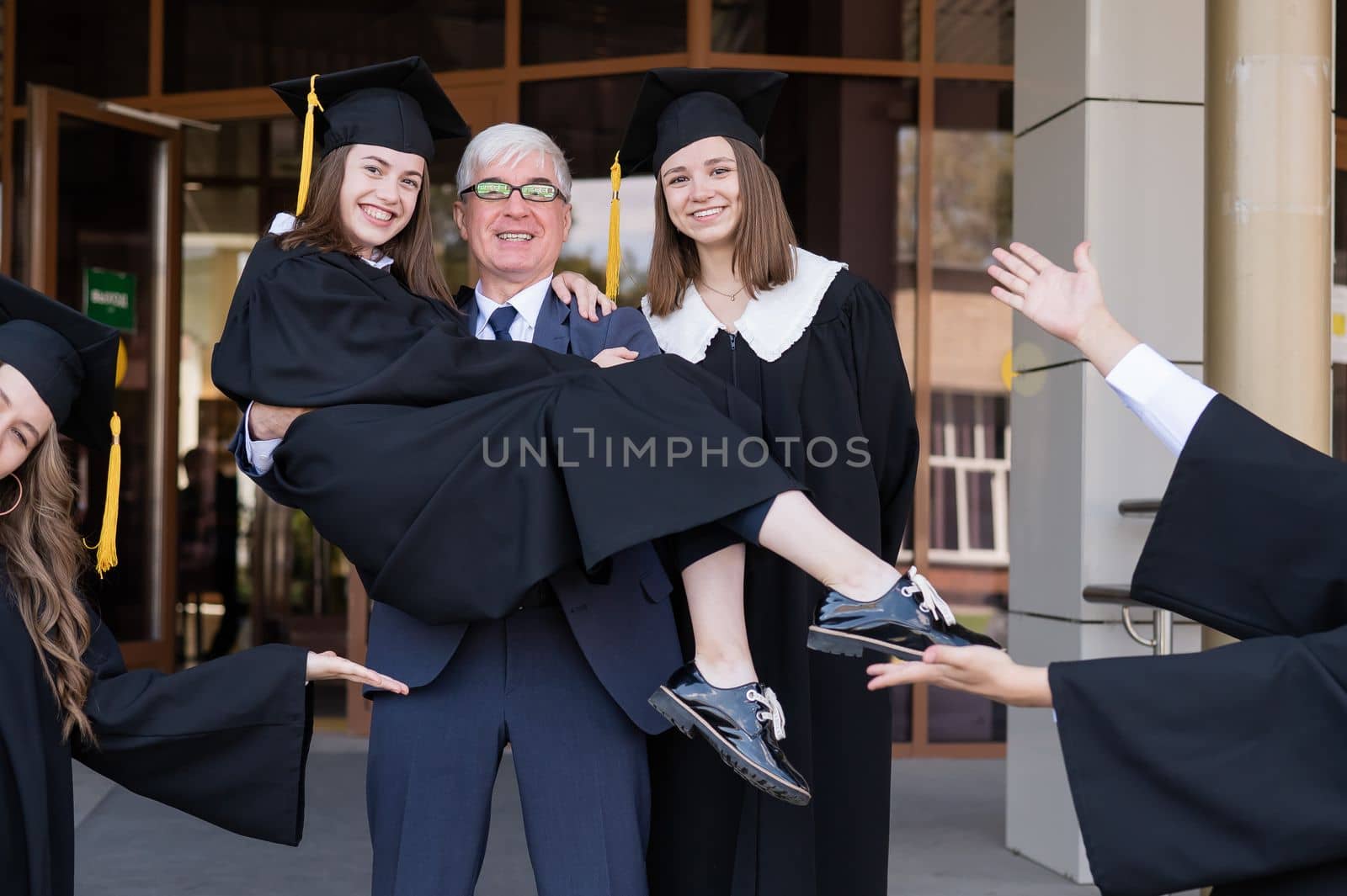 The teacher holds the graduate in his arms