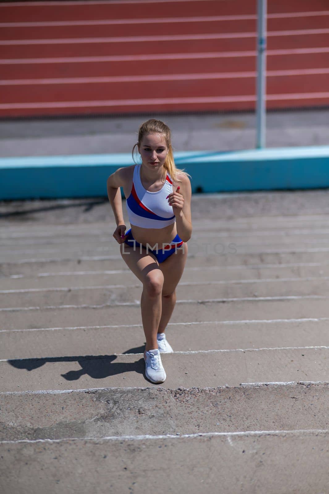 Young caucasian woman running on stadium stairs outdoors. by mrwed54