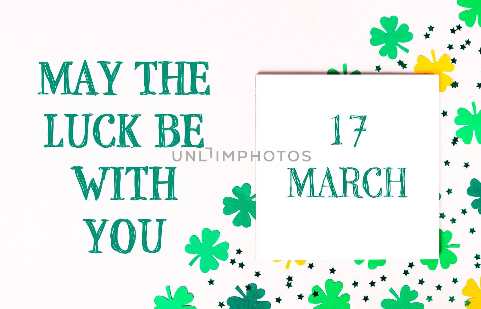 May The Luck Be With You. Composition for St. Patrick's Day. Congratulatory white card calendar with clover on a white background. Top view, lie flat, copy space