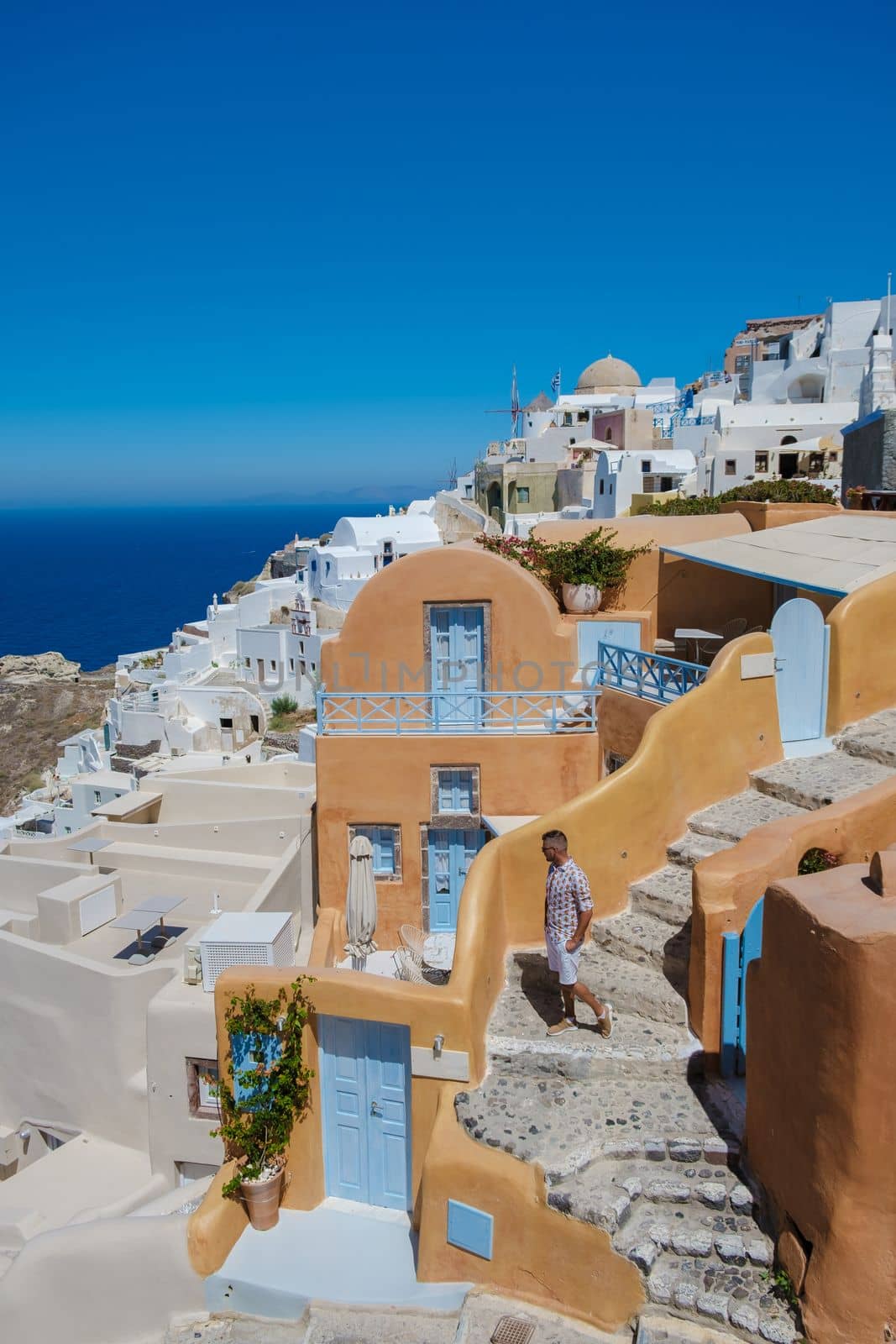 Couple visit Santorini Greece, men and women visit the whitewashed Greek village of Oia during summer vacation at sunrise over the blue domes and white churches