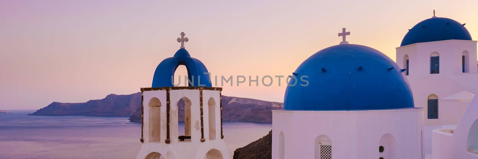 White churches an blue domes by the ocean of Oia Santorini Greece, traditional Greek village  by fokkebok