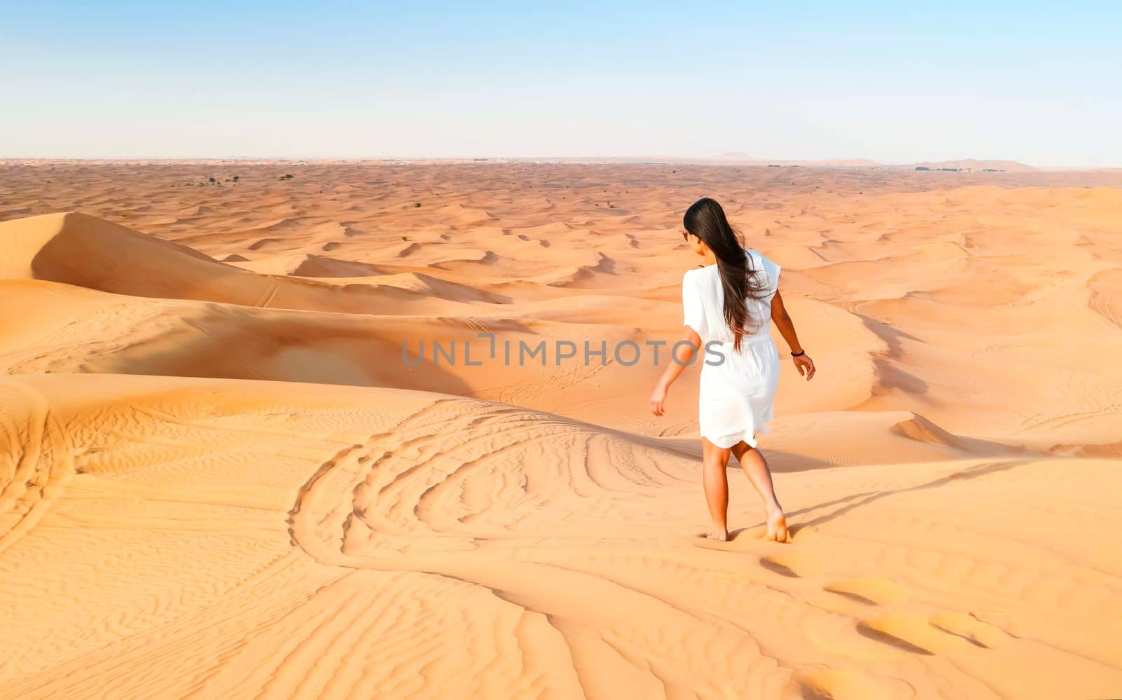 Young Asian woman walking in the desert, Sand dunes of Dubai United Arab Emirates, by fokkebok