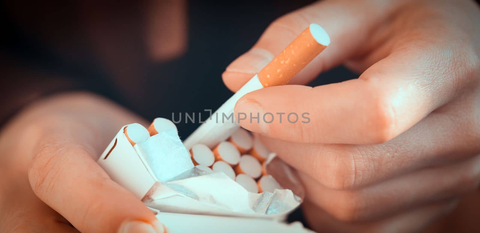 A man holds a pack of cigarettes in his hands, hand with a cigarette closeup. Person with a bad habit that is unhealthy