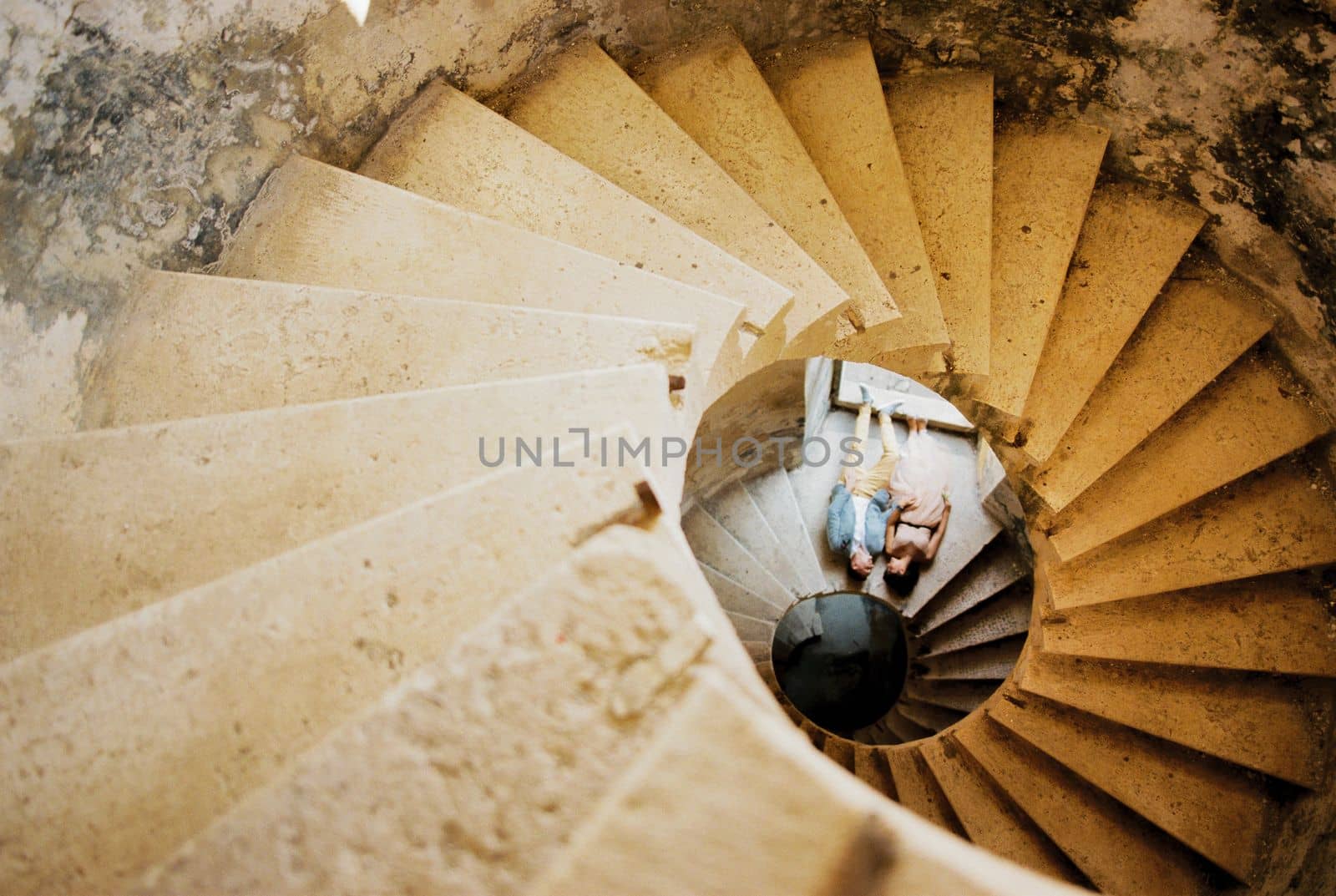 Bride and groom lie at the base of the spiral staircase. Top view. High quality photo