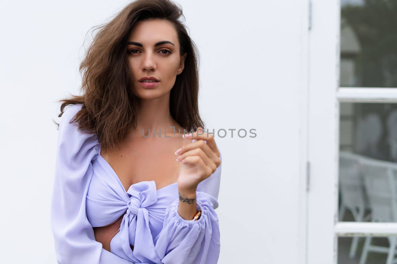 Pretty young stylish woman in trendy purple crop top long sleeve, isolated, white wall, natural day light..