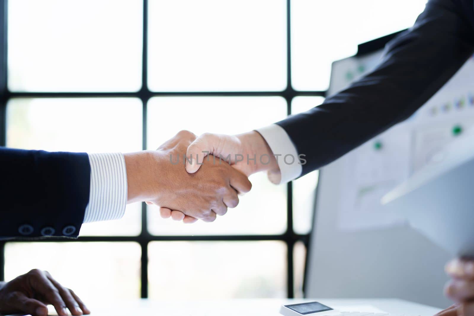 Asian entrepreneurs handshakes to congratulate the agreement between the two companies to enhance investment and financial strength. deal concept by Manastrong