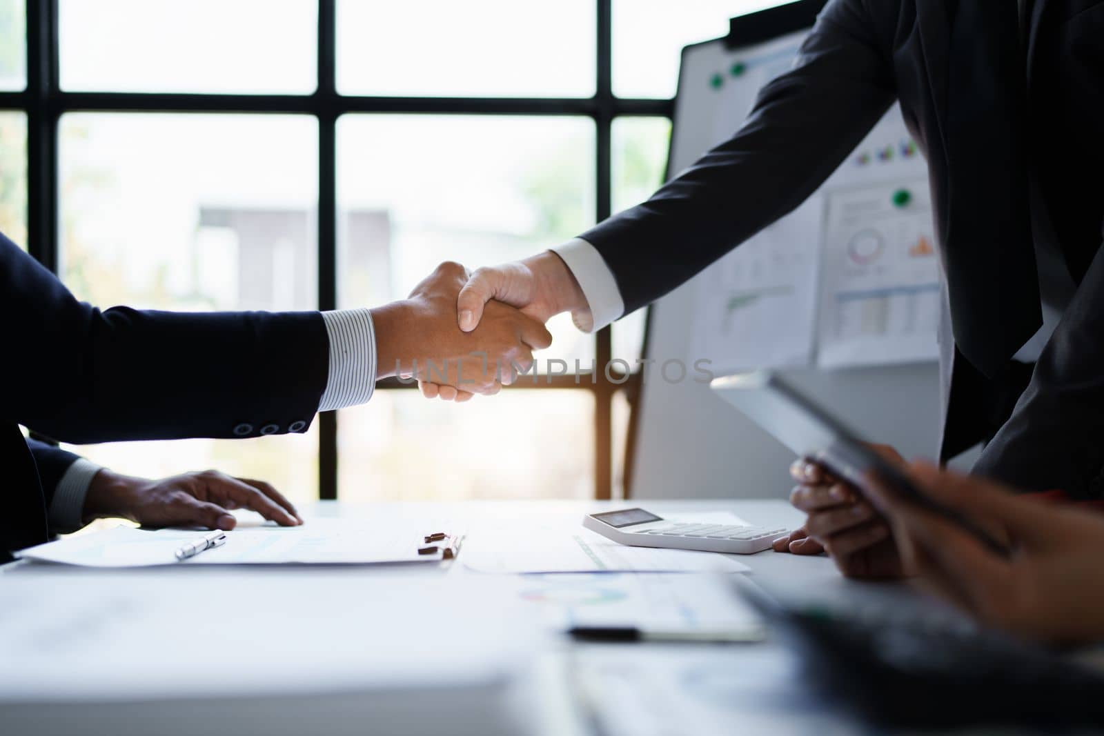 Asian entrepreneurs handshakes to congratulate the agreement between the two companies to enhance investment and financial strength. deal concept.