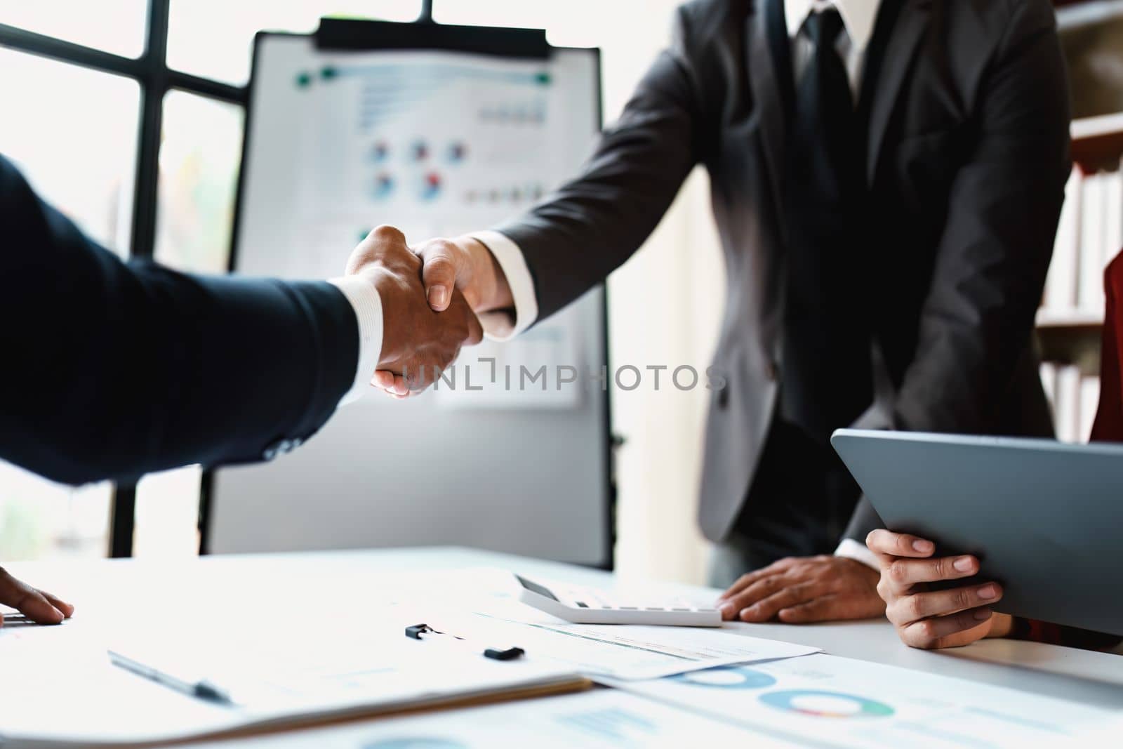 Asian entrepreneurs handshakes to congratulate the agreement between the two companies to enhance investment and financial strength. deal concept by Manastrong