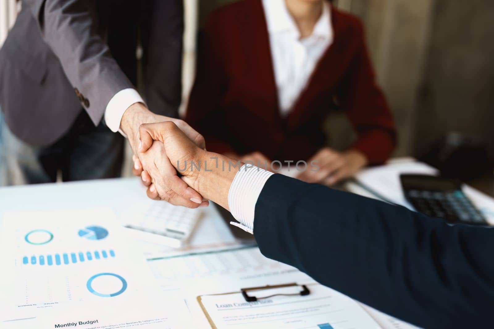 Asian entrepreneurs handshakes to congratulate the agreement between the two companies to enhance investment and financial strength. deal concept by Manastrong