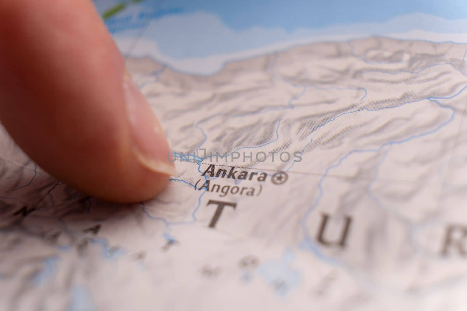 Close up of finger pointing to Ankara, Turkey on colorful map with selective focus, shallow depth of field, background blur. High quality photo