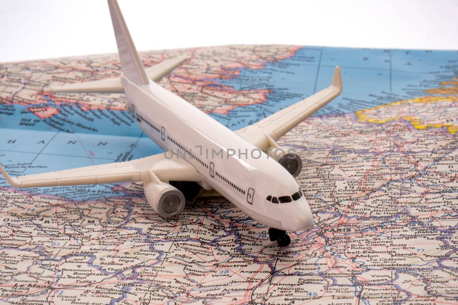 Close up of a miniature passenger plane on a colorful map showing Europe, Paris through selective focus, background blur. High quality photo