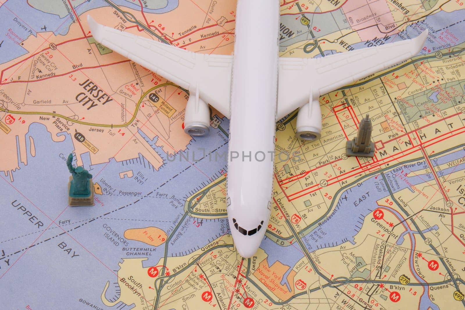 Close up bird's eye view of Manhattan, New Jersey map detail with a miniature passenger plane, Statue of Liberty and Empire State building figures . High quality photo