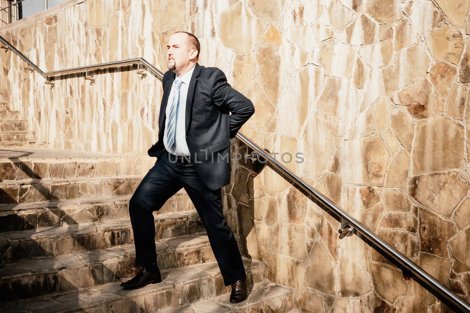 Portrait of a senior professional man in a suit with various problems. A middle-aged businessman with a briefcase descends the stairs.