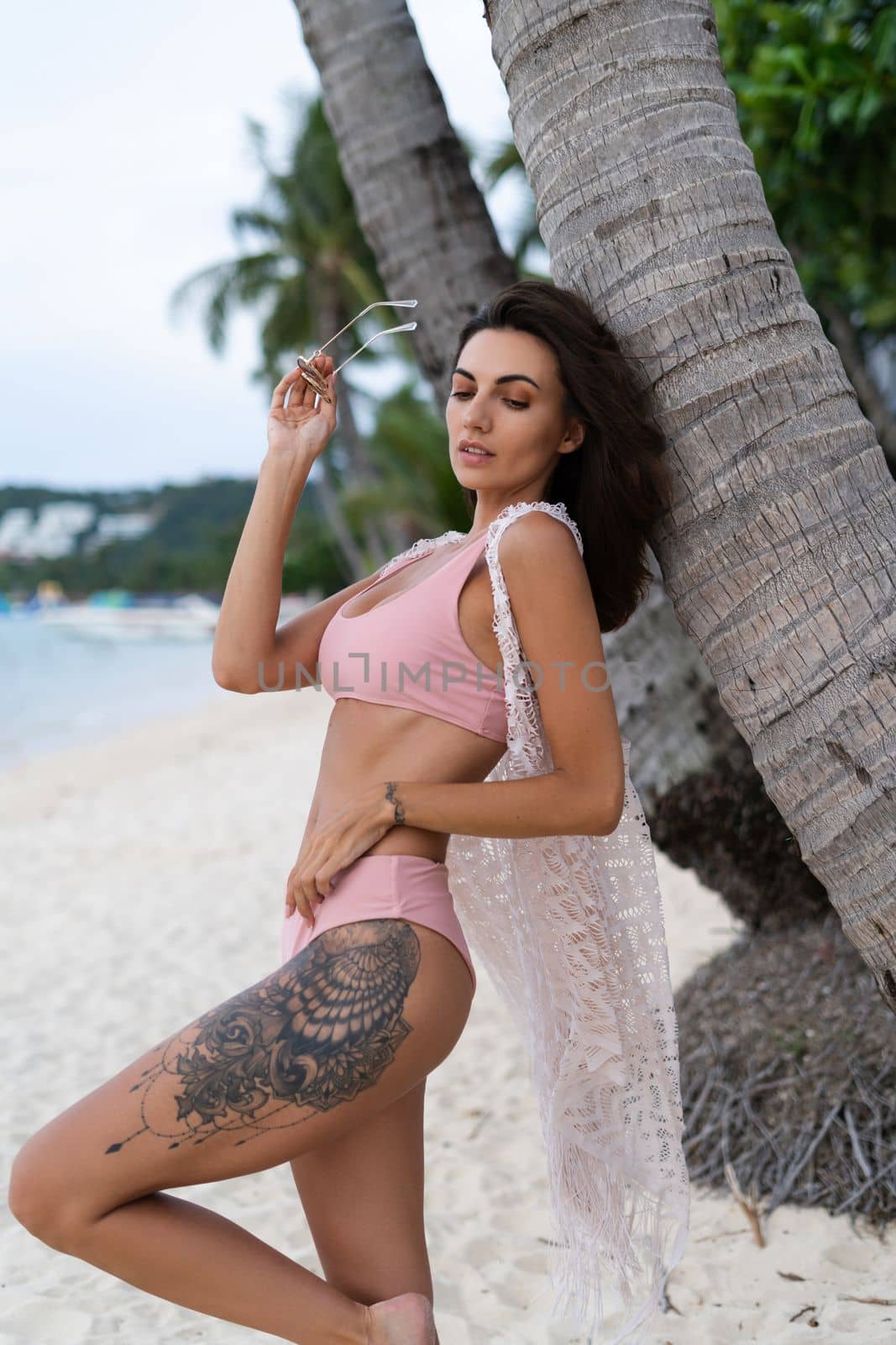 Stylish young woman with voluminous hair in a bikini and lace pareo posing on a tropical beach, slim, tanned, athletic, sunglasses by kroshka_nastya