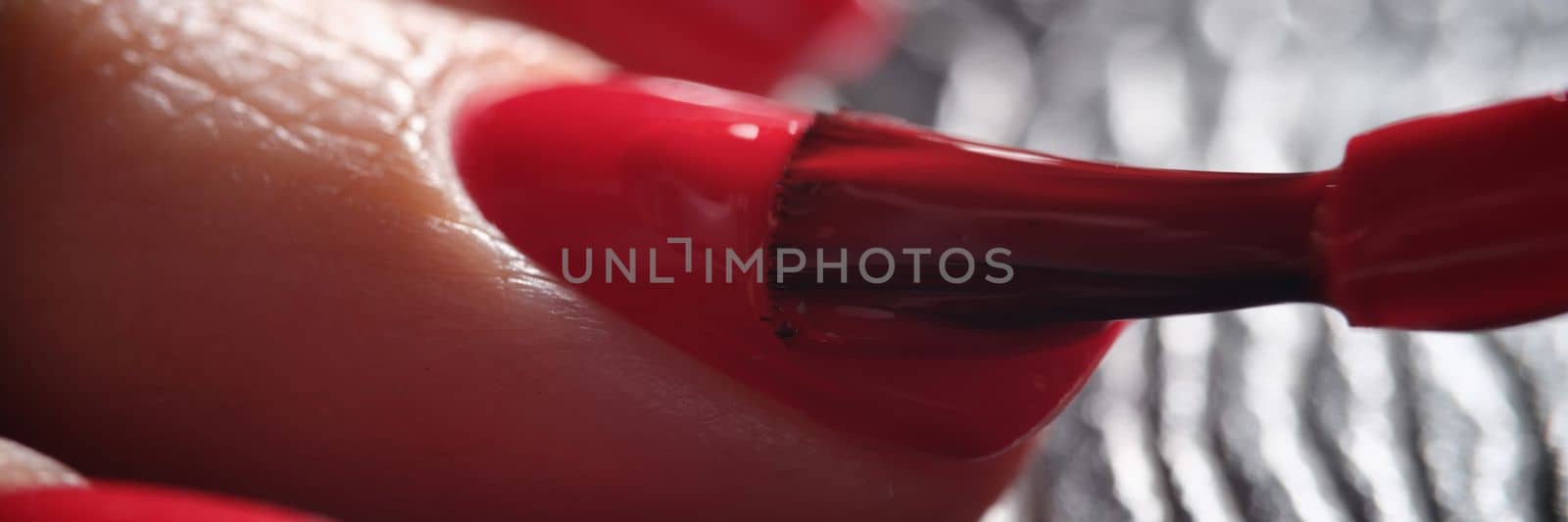 Red nail polish is applied to hand closeup by kuprevich