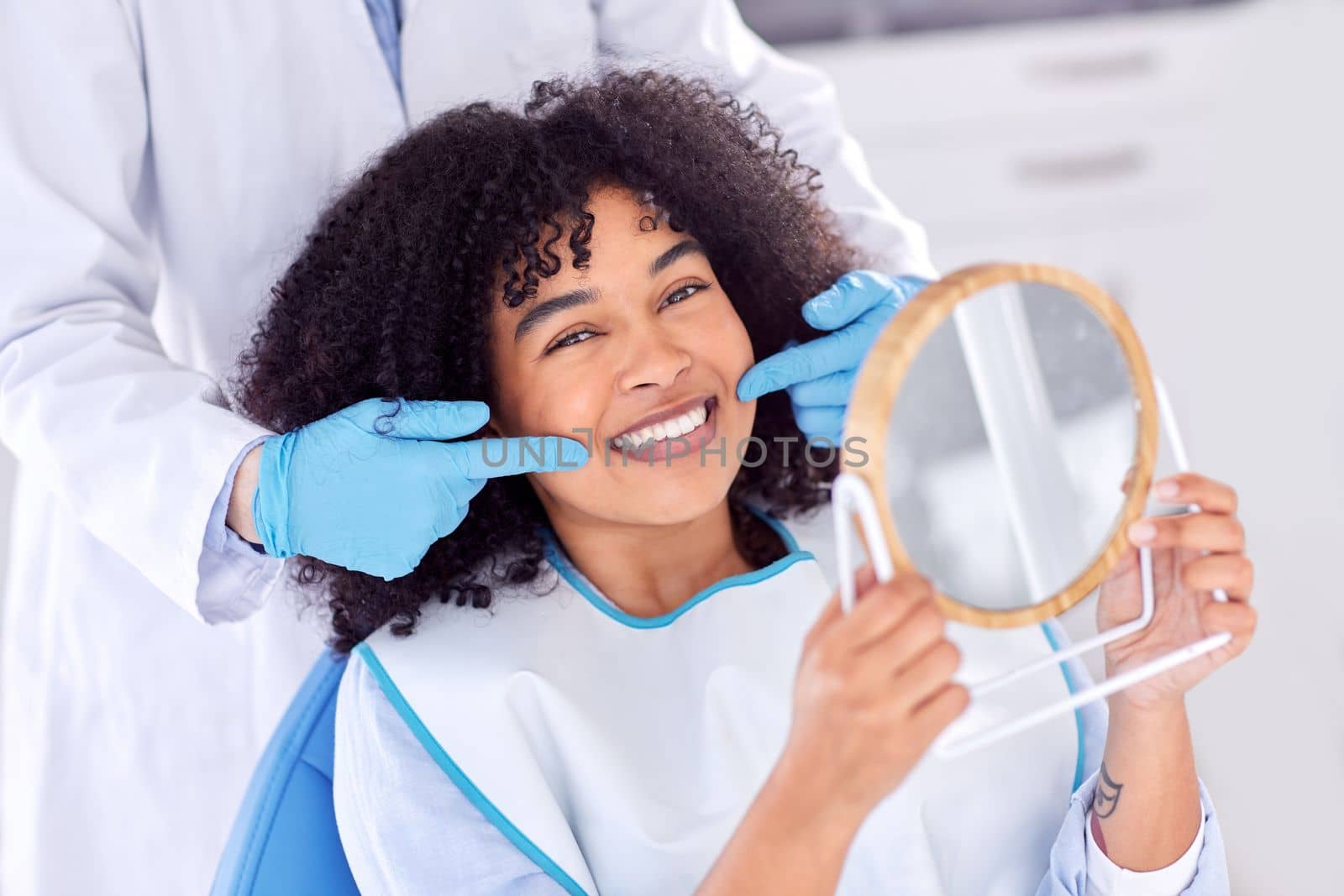 Just brush the teeth you want to keep. a young woman checking her dental work in a mirror. by YuriArcurs