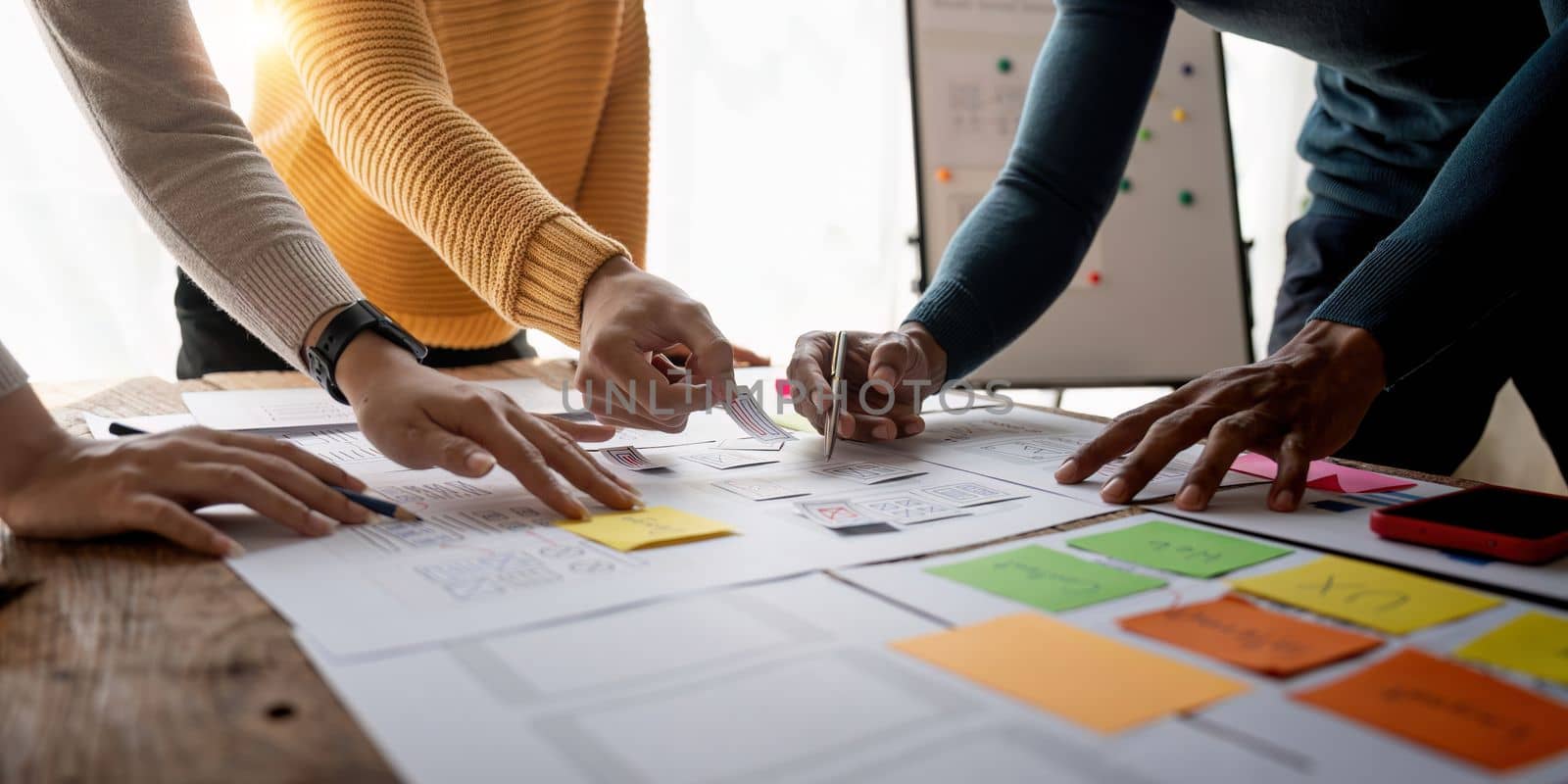 Close up ux developer and ui designer brainstorming about mobile app interface wireframe design on table with customer brief and color code at modern office.Creative digital development agency.panning by nateemee