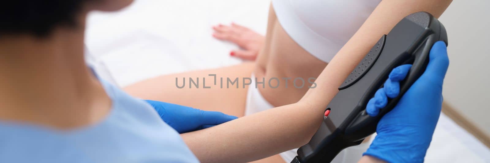 Woman hand in glove makes skin correction on arm for patient using special device. Laser hair removal on arms