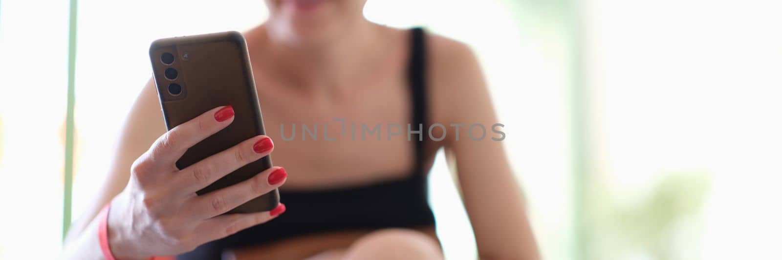 Smiling woman holding smartphone and looking at positive information by kuprevich