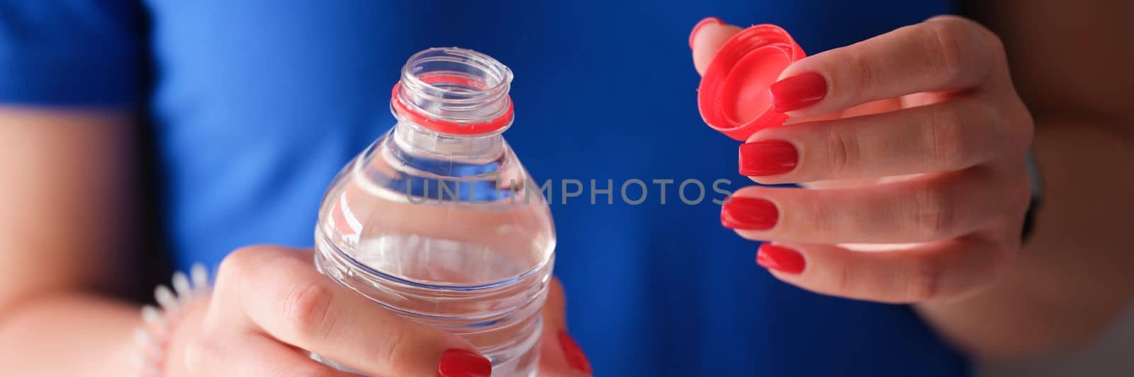 Woman opening plastic bottle with clean water. by kuprevich