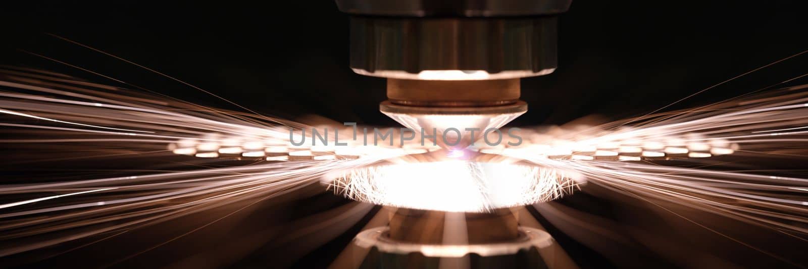 Laser cutting of metal sheet in production closeup. Sparks fly out machine head for metal processing