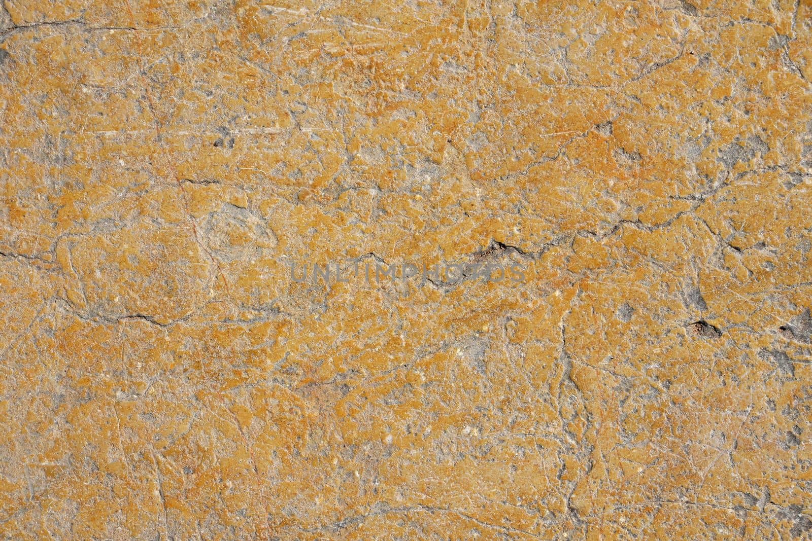 Grunge yellow orange brown old painted concrete or stone wall background texture with stains of faded paint peel and scaling, uneven and weathered