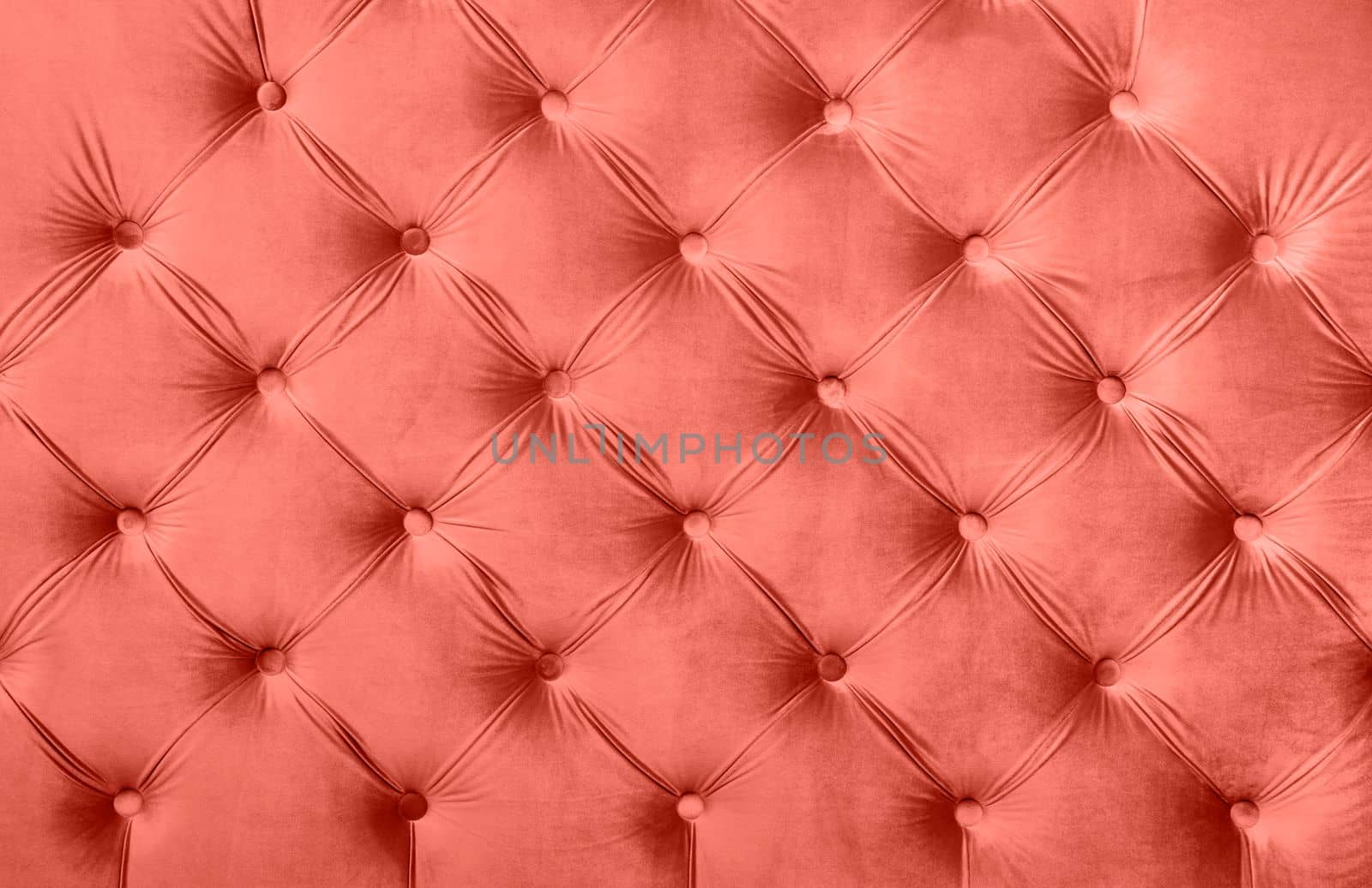 Coral toned pink velvet capitone textile background, retro Chesterfield style checkered soft tufted fabric furniture decoration with buttons, close up