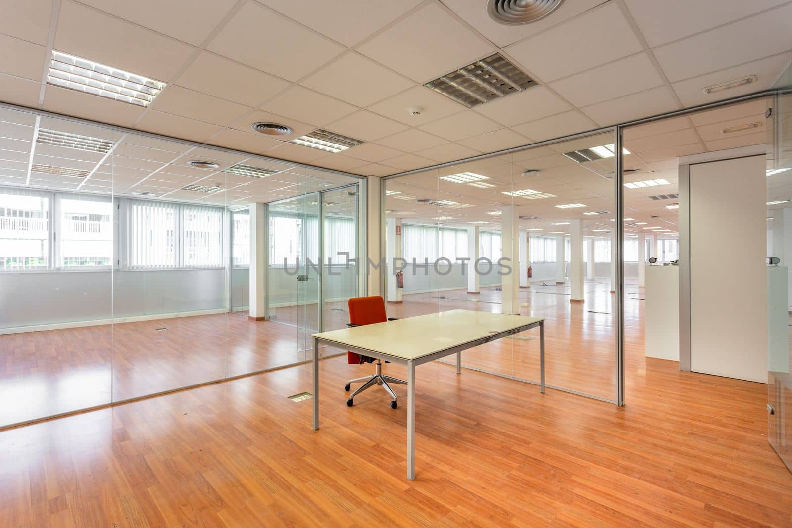 In a bankrupt office building, one of the many empty rooms with transparent, solid glass wall panels and an outdated ceiling covering is in need of repair and refurbishment. by apavlin