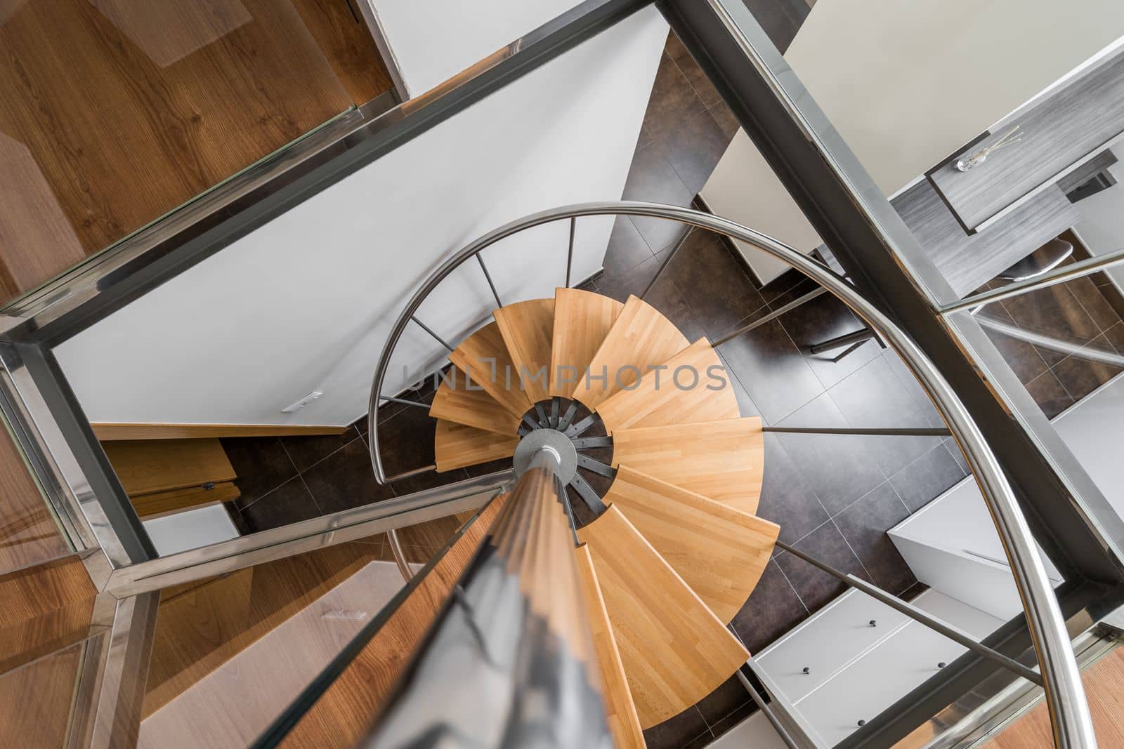 Modern spiral staircase with wooden steps and metal railings looking down from above creates a feeling of weightlessness. Stylish staircase with beautiful architecture in houses with trendy design