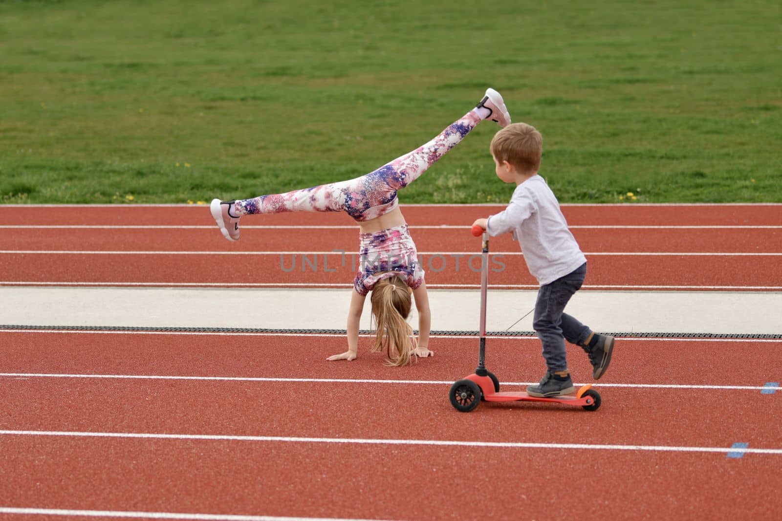 Brother looks at sister who plays sports at the stadium by Godi