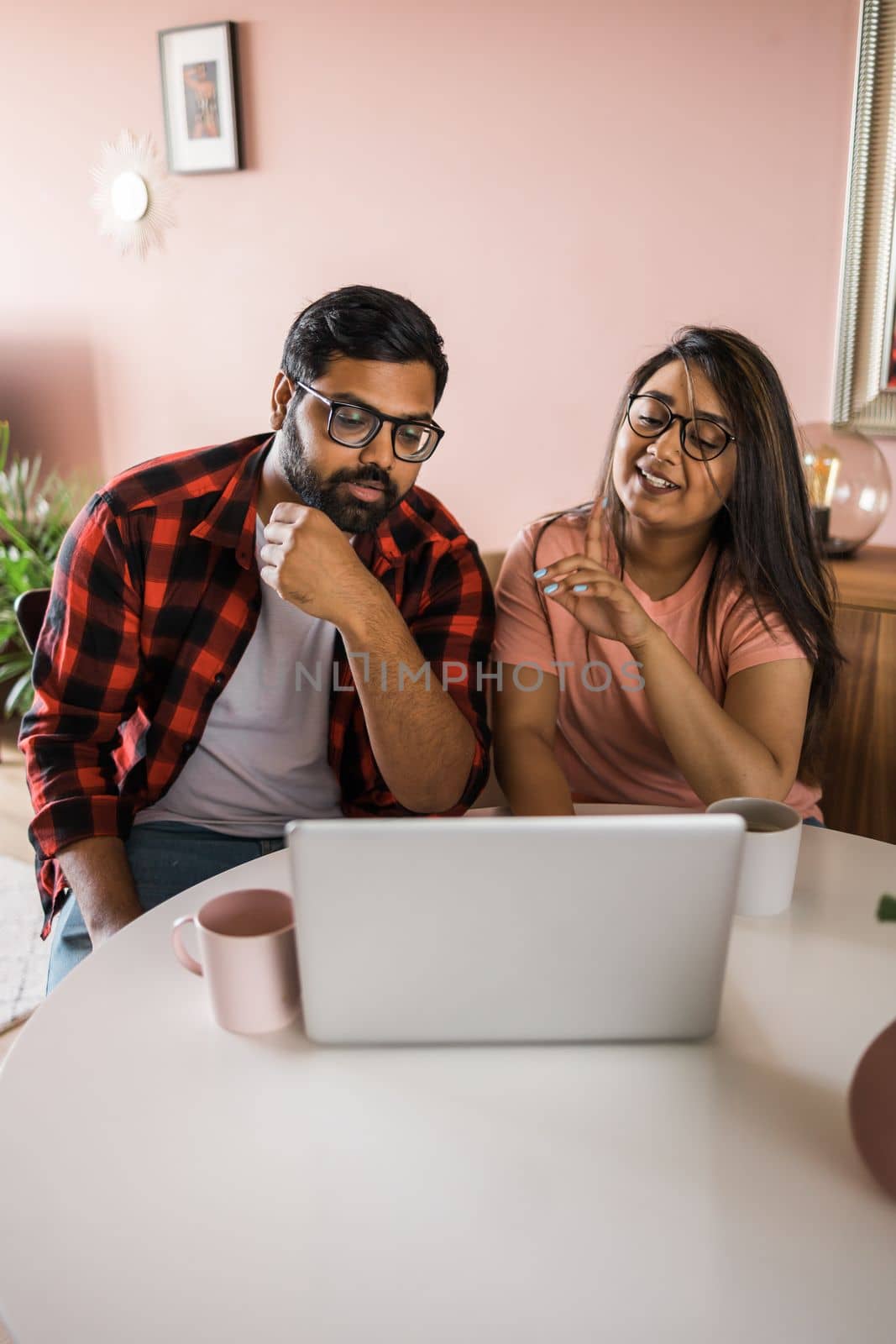 Latino or indian man and woman couple use their laptop in the living room to make video calls. Video call and online chat with familys