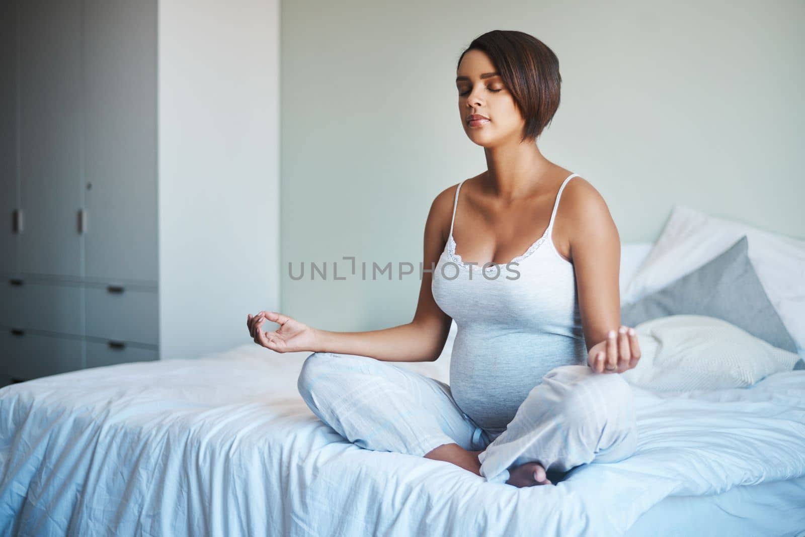 Yoga is good for both mother and child. Full length shot of a pregnant young woman practicing yoga inside her bedroom at home. by YuriArcurs