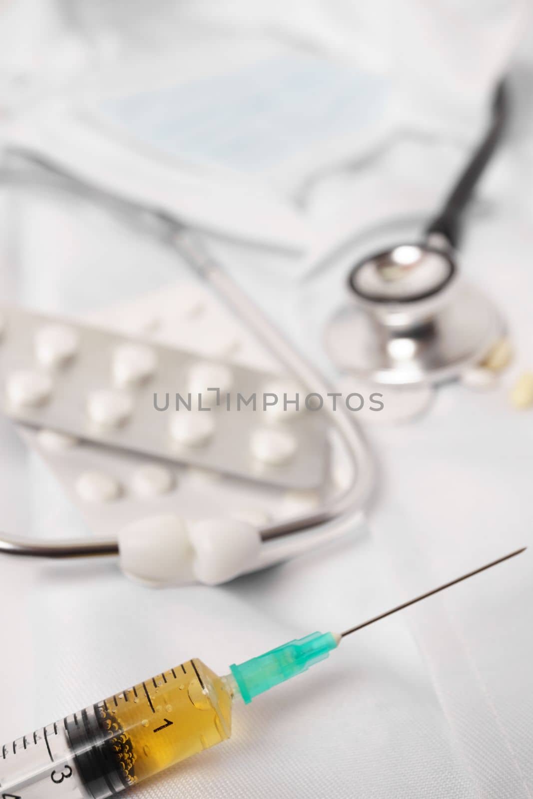 syringe, stethoscope and pills on a doctor's gown white background and copy space