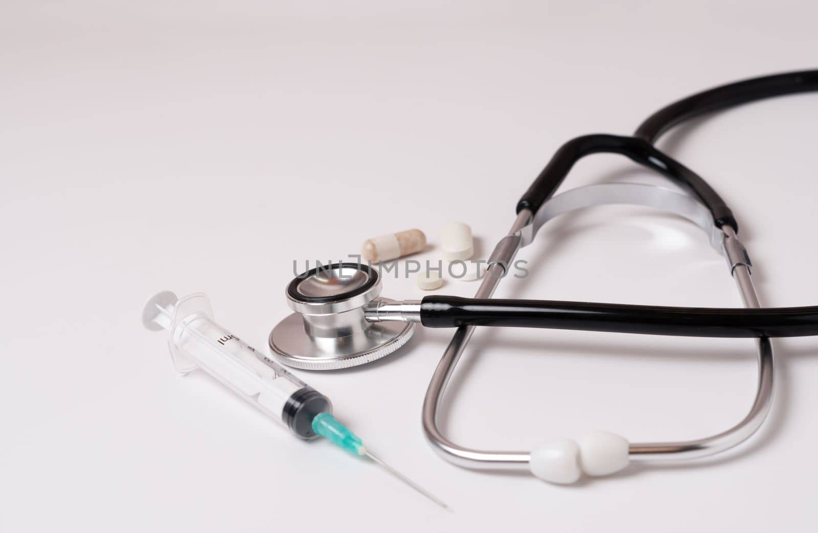 syringe, stethoscope and pills on a white doctor's gown by joseantona